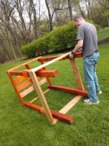 A man constructs a wooden structure that is lying on its side.